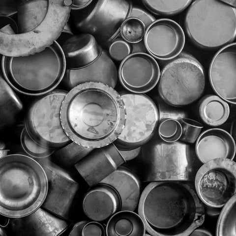 Assortment of round aluminum can ends and small metal containers stacked closely together.