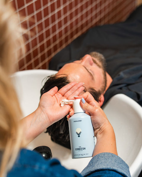 woman conditioning mans hair in sink with highlands condish