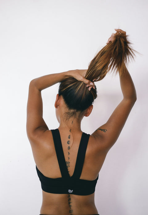 Woman slicking her hair back into a ponytail