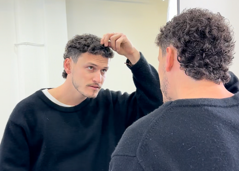 man looking at mullet in the mirror