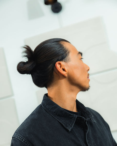 Man with straight black hair in a bun