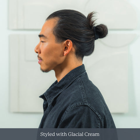 Profile of man with topknot wearing dark coat against pale background — Styled with Glacial Cream