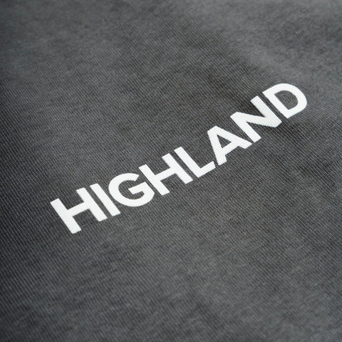 Gray t-shirt fabric close-up showing white HIGHLAND wordmark.