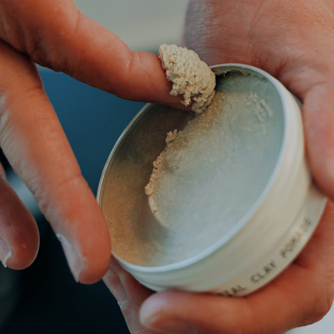Hand scooping pomade from a small metal tin
