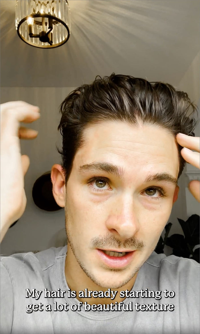 Close-up of a man styling slicked-back hair with his hands; overlay text reads 