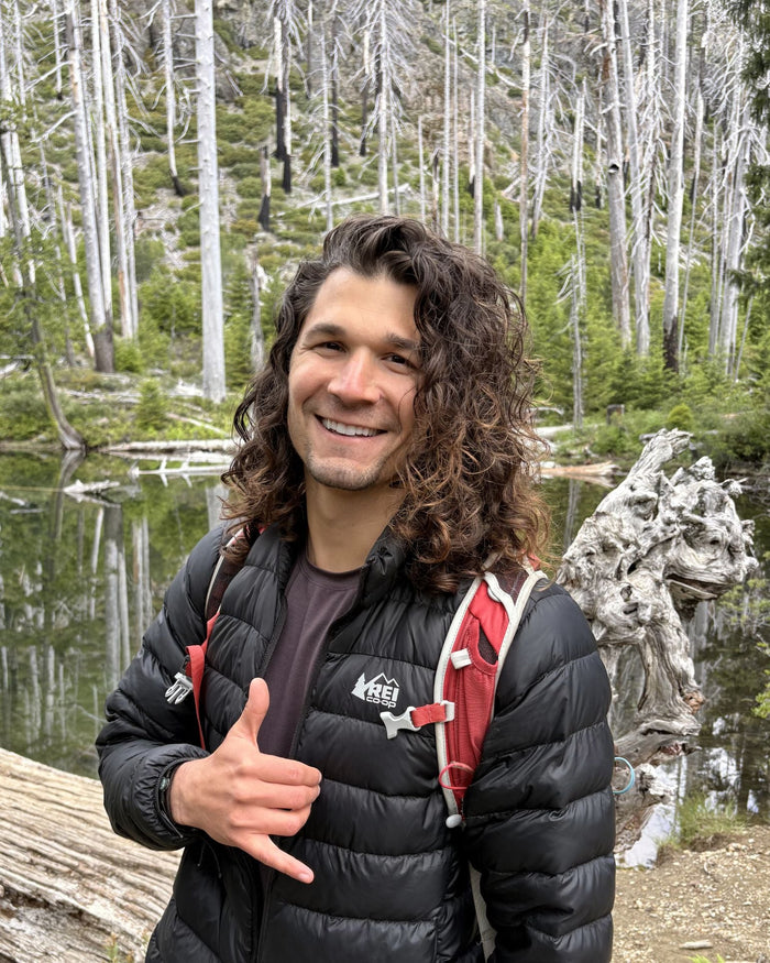 Man with curly hair outside in the woods