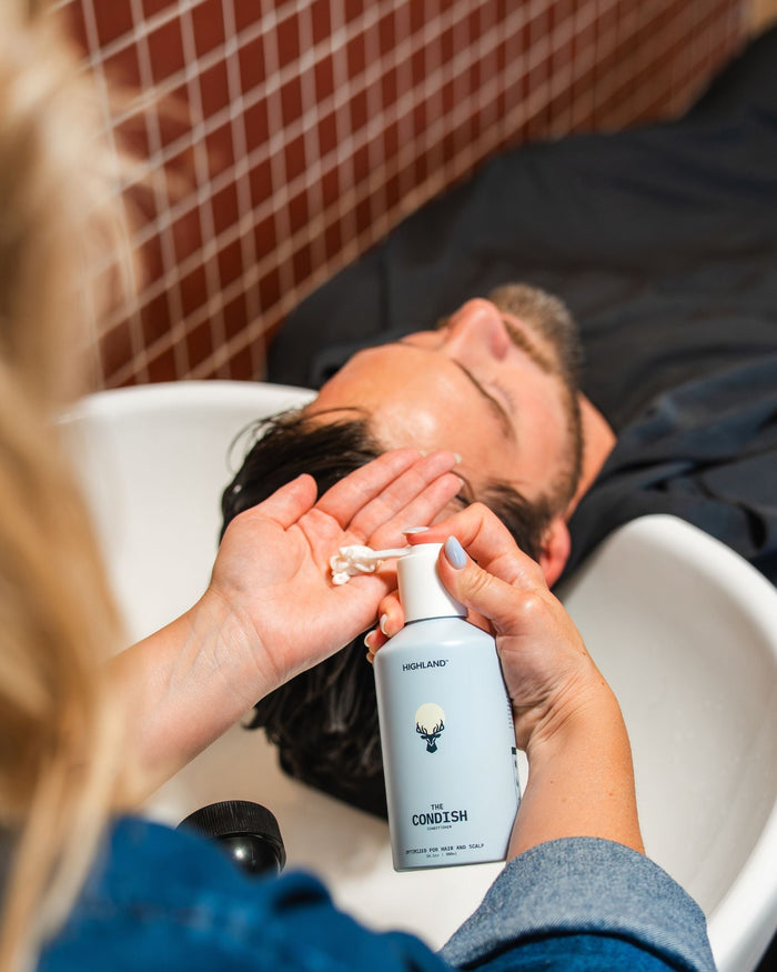 woman conditioning mans hair in sink with highlands condish