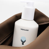 Close-up of Highland Dopp Kit showcasing its brown zippered exterior around a white pump bottle