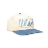 Cream baseball cap with blue brim, &#39;HIGHLAND&#39; printed across the front