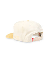 Off-white five-panel cap, back view showing adjustable strap and red brand tab.