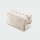 Angled view of Highland Dopp Kit showcasing its top zipper, side handle, and embossed logo on a light gray background