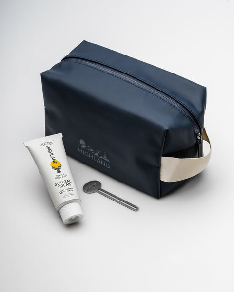 Angled view of Highland Dopp Kit showing zippered compartment and carry handle with Glacial Cream and tool on white background